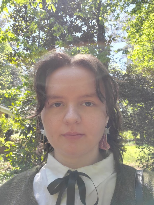 a selfie of Ella, a white brunette woman, standing outside in the sun